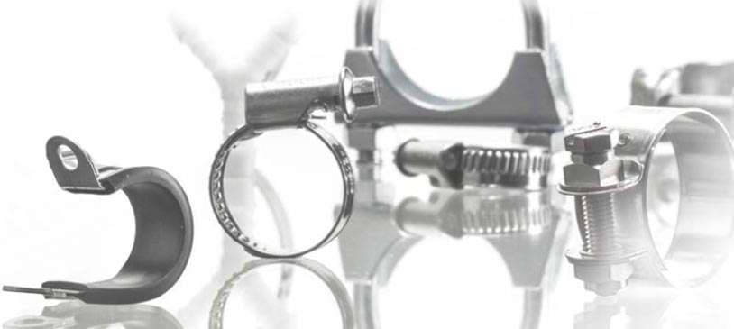Eine Nahaufnahme verschiedener Metall-Befestigungsschellen und Klemmen, darunter Schlauchschellen, Rohrschellen und gummierte Clips, auf einem hellen, reflektierenden Untergrund.